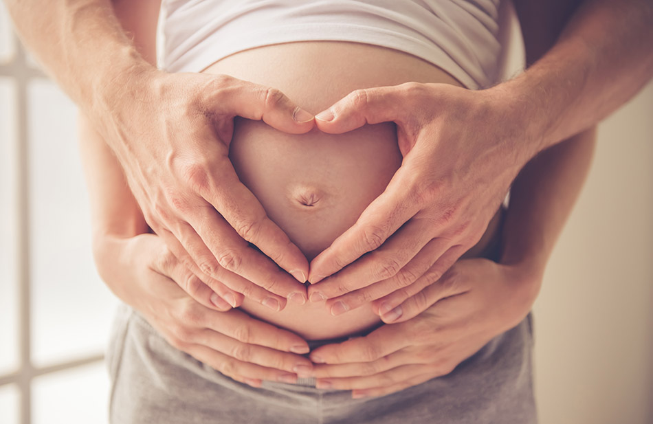 Cropped image of beautiful pregnant woman and her handsome husband hugging the tummy